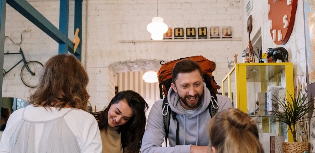 Backpackers cheerfully checking in at a vibrant hostel reception desk.