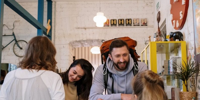 Backpackers cheerfully checking in at a vibrant hostel reception desk.